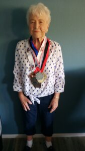 Jo Hancock, posing for a photo with some of the medals she's won at pickleball tournaments over the years.